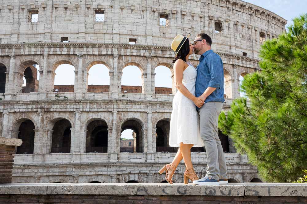 Standing on a ledge kissing before the Roman Colosseum view