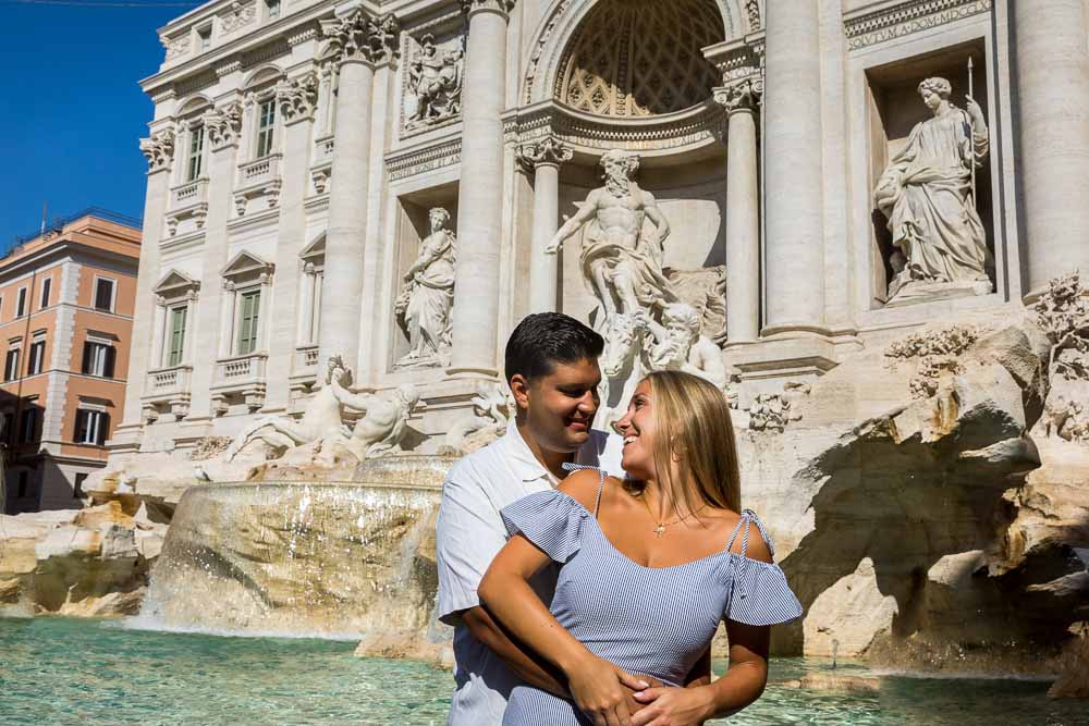 Couple posing while taking photos at the Trevi fountain