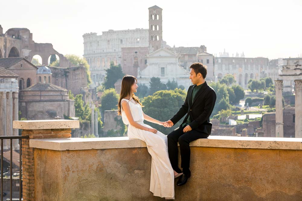 Holding hands before the scenic view of ancient Rome with the Coliseum in the far distance