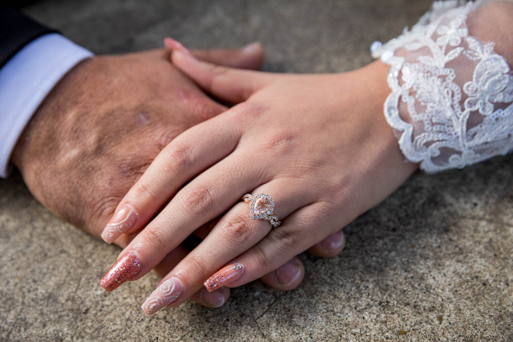 The engagement ring photographed on the hand of the bride over the groom's hand