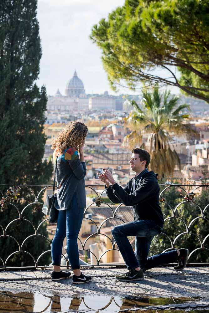 Knee down surprise wedding marriage proposal photographed with Saint Peter's dome in the far distance