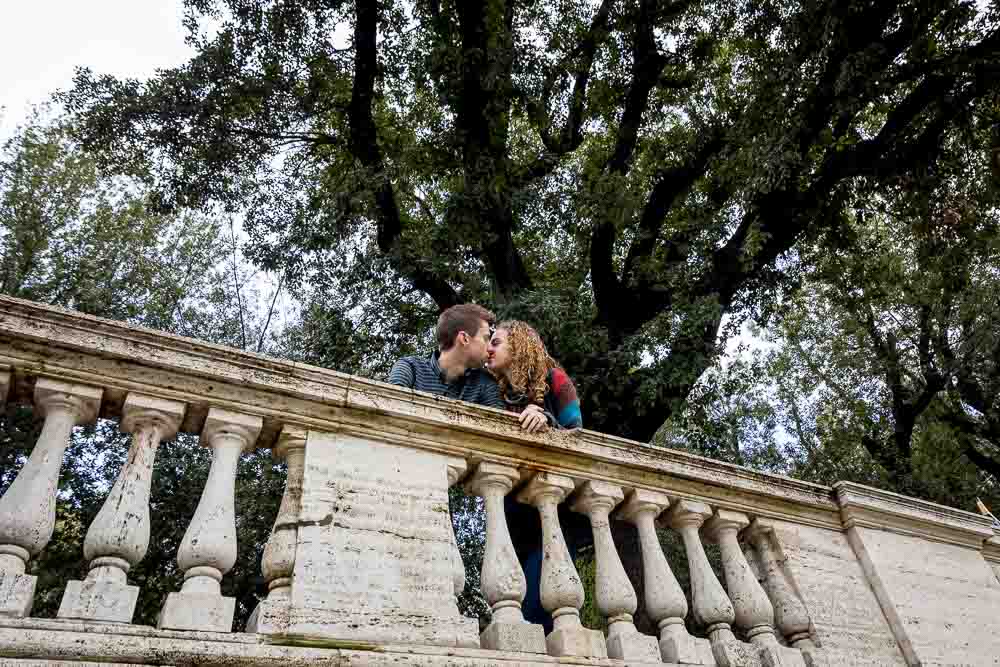 Romantic image of a couple in love underneath a large green tree in Rome' Villa Borghese park