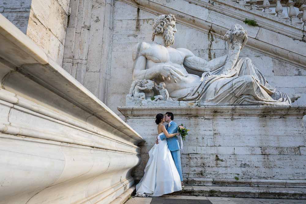 Romantic wedding photography set underneath an ancient roman marble statue found in Piazza del Campidoglio in Rome Italy.