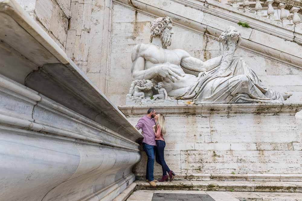 Kissing under a large marble statue in Rome Italy photoshoot