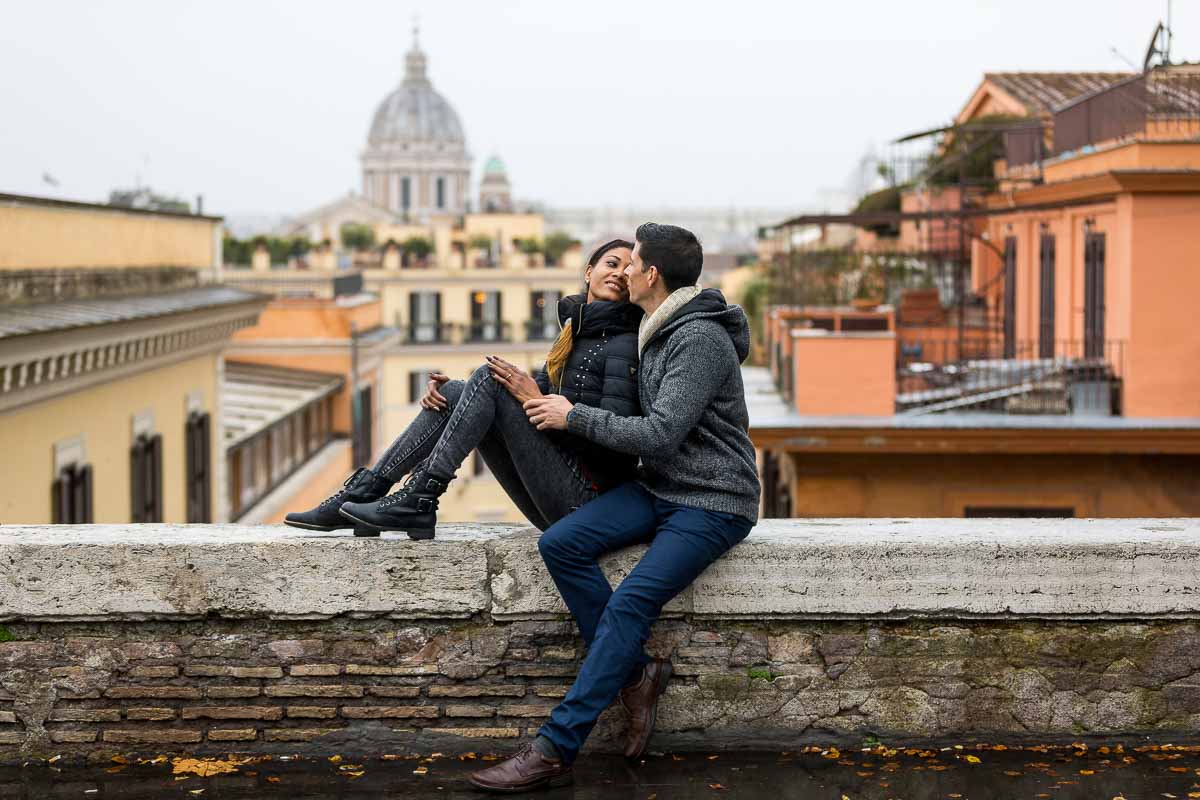 -Couple portrait picture while sitting down before the distant view. Rome, Italy.