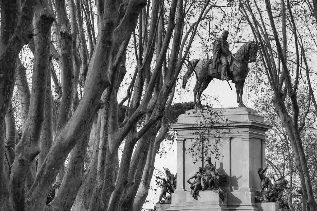 The Garibaldi statue seen through trees at Piazzale Garibaldi in Rome. Image in black and white