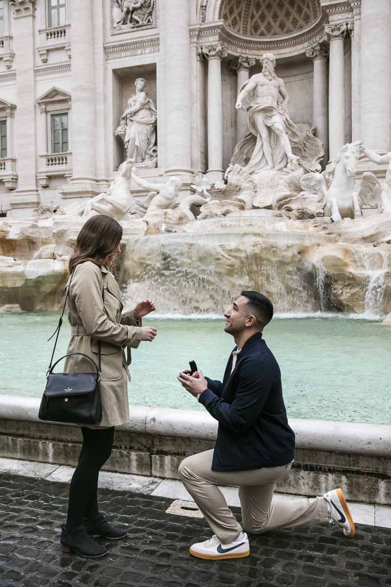 Man kneeling down to ask the most important question! A romantic proposal moment photographer at the Trevi fountain