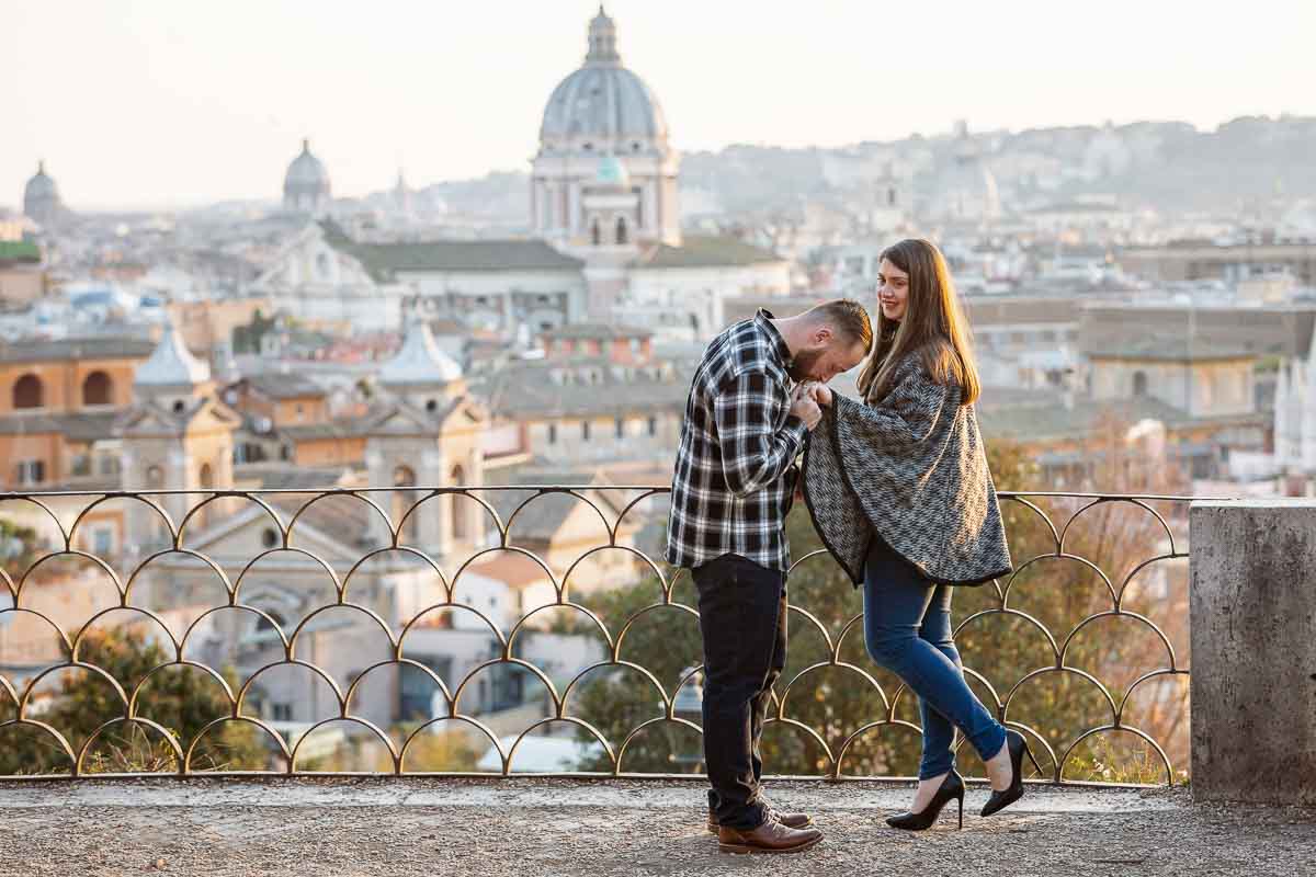 A gesture of chivalry during and engagement photo session overlooking the city of Rome from the above pincio terrace overlook