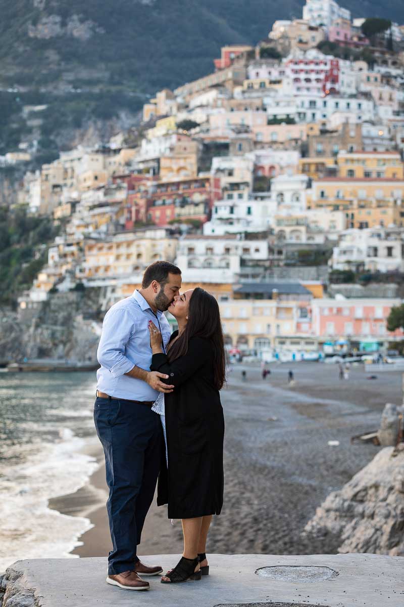 Couple kissing on the beach with the town in the background