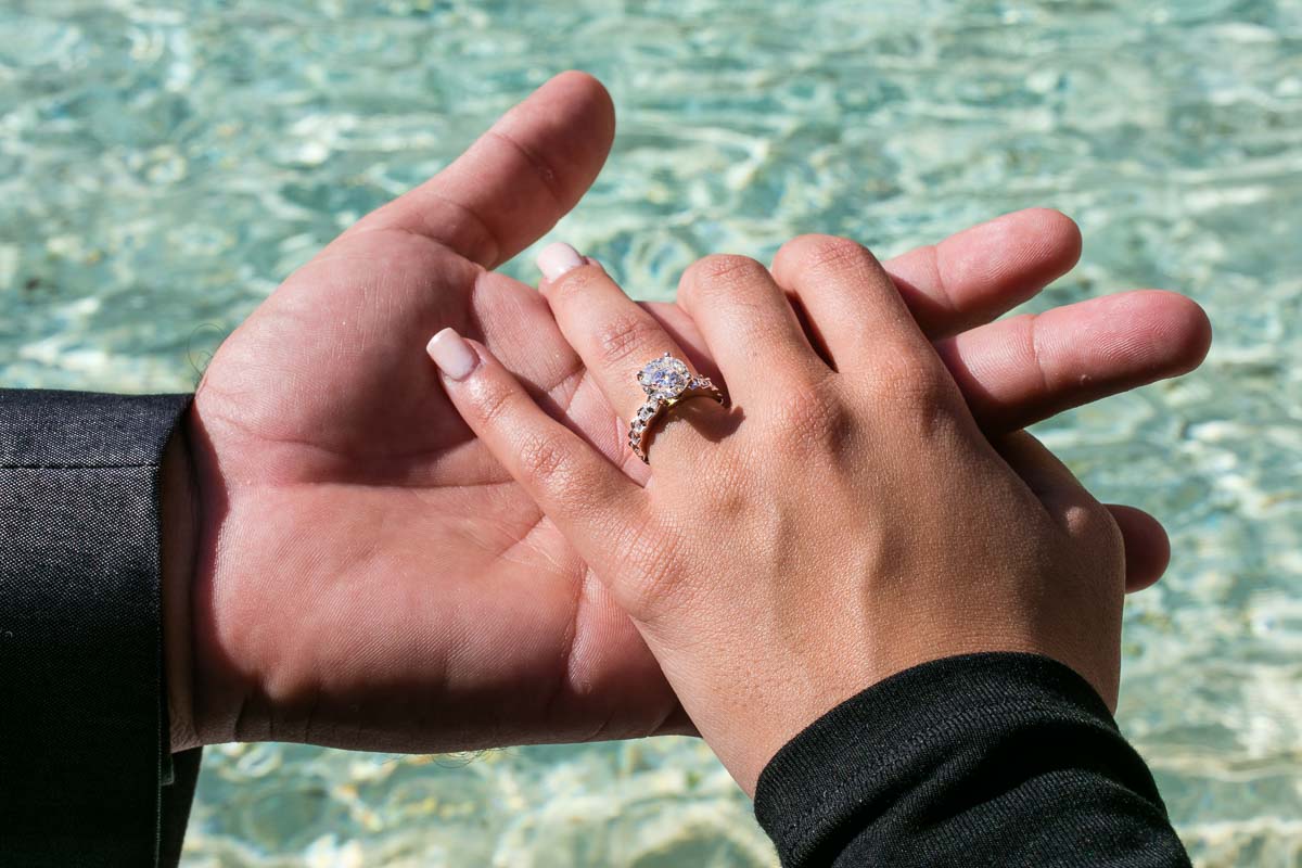 Photo of the engagement ring photographed over emerald green water