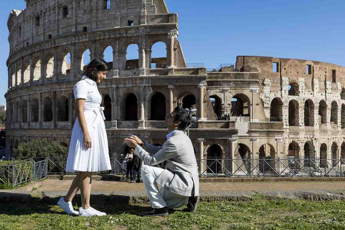 Knee down wedding marriage proposal from the ancient forum with a view over the roman colosseum as backdrop