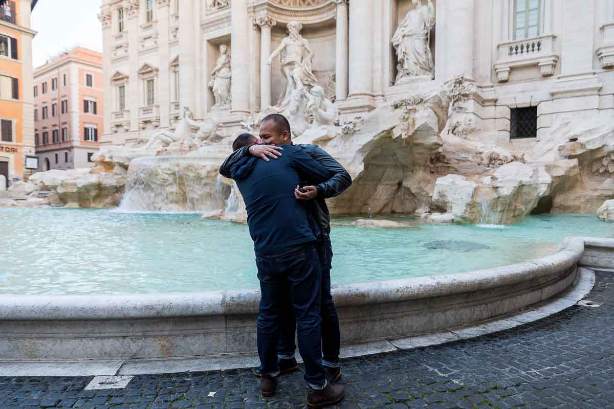 Just engaged same sex couple hugging next to the Trevi water fountain