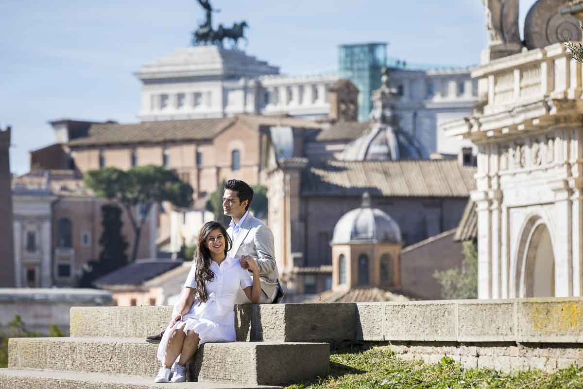Couple portrait picture sitting down on the steps with the distant city as backdrop