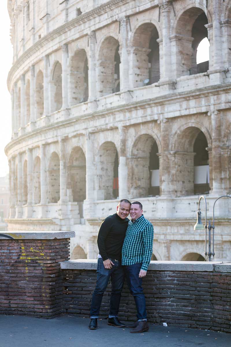 Couple close together posing in front of the Roman Colosseum