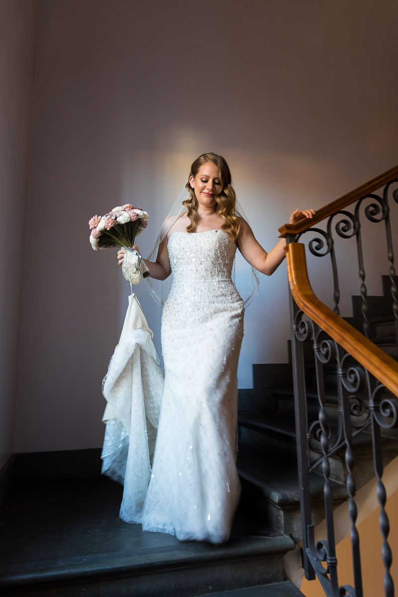 Bride descending stairs next to natural daytime light shining through the window