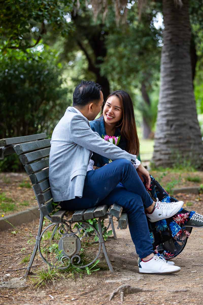 Couple sitting down on a park bench in a park like setting during a session with professional photographers