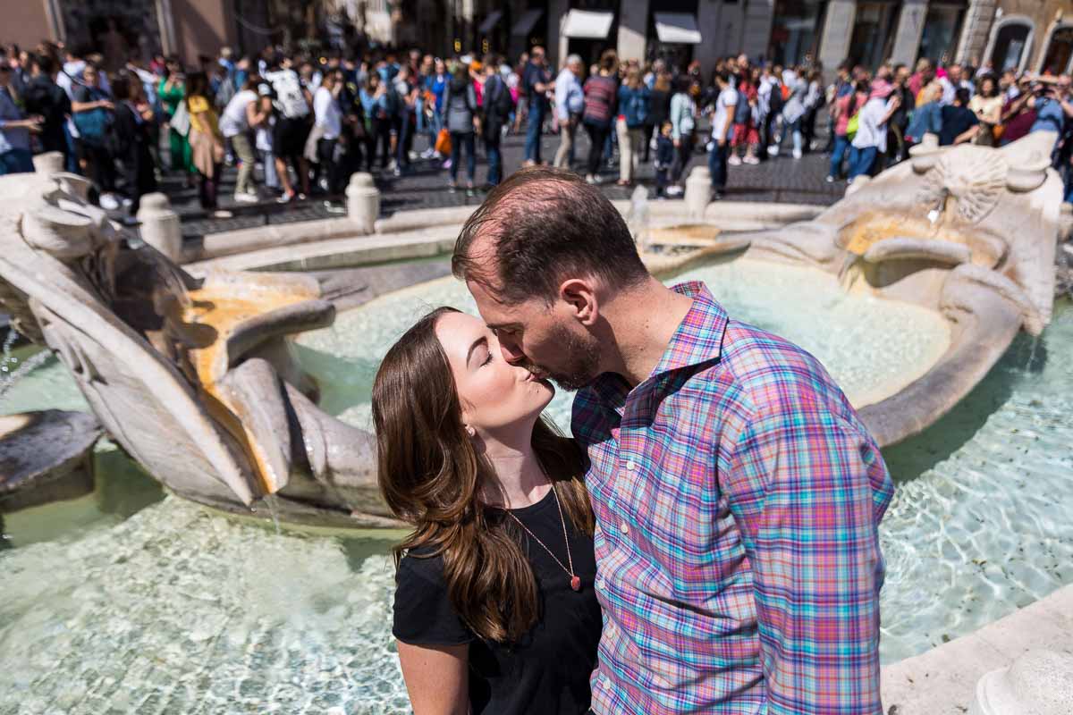 Romantic kiss by the Barcaccia water fountain found in Piazza di Spagna Rome Italy