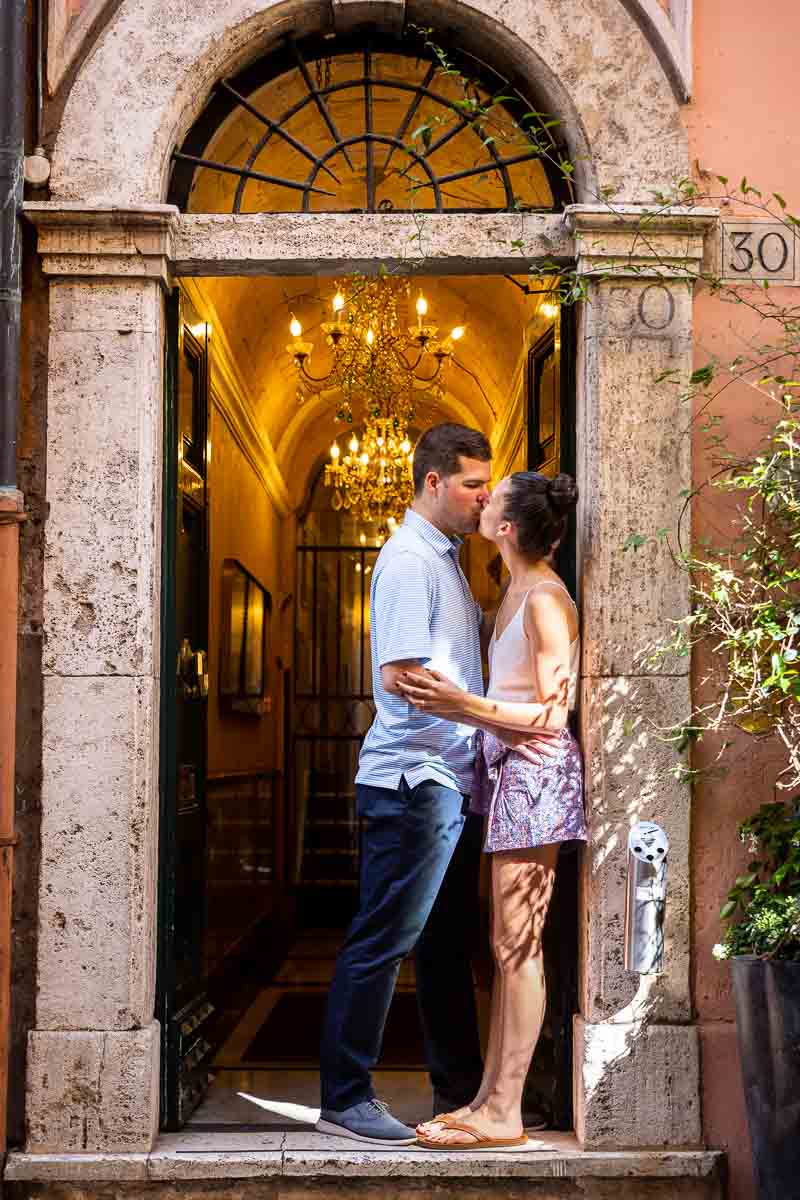 Couple kissing image standing on the front steps of an Italian palazzo building with warm chandelier light