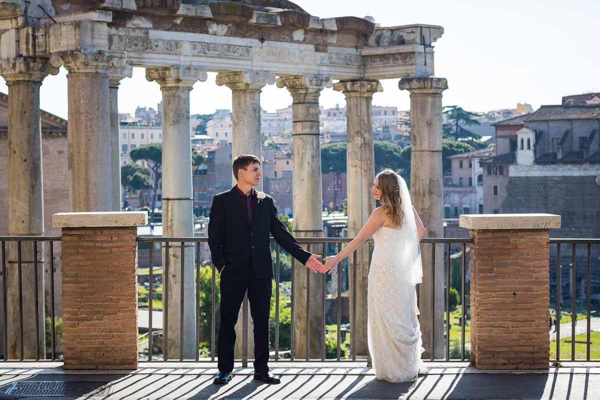 Wedding couple holding hands before the ancient scenery of the roman forum