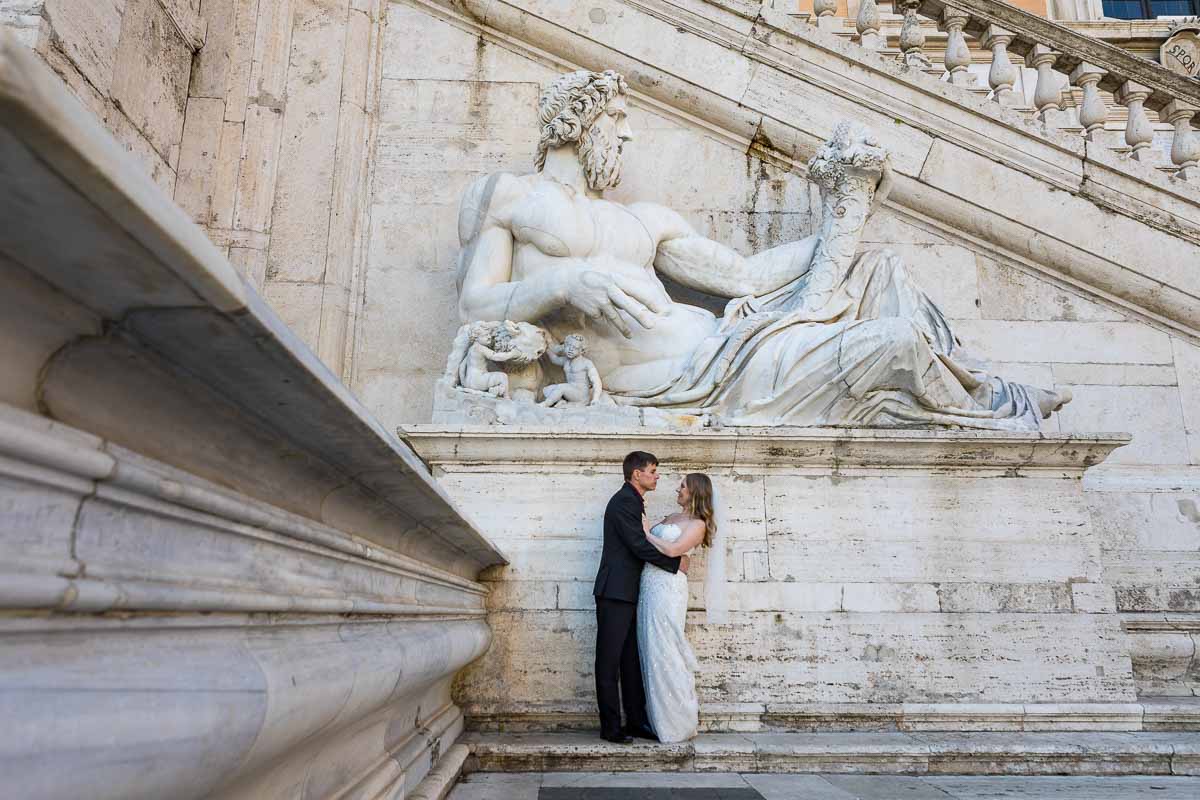 Portrait standing and posing underneath a large marble roman statue