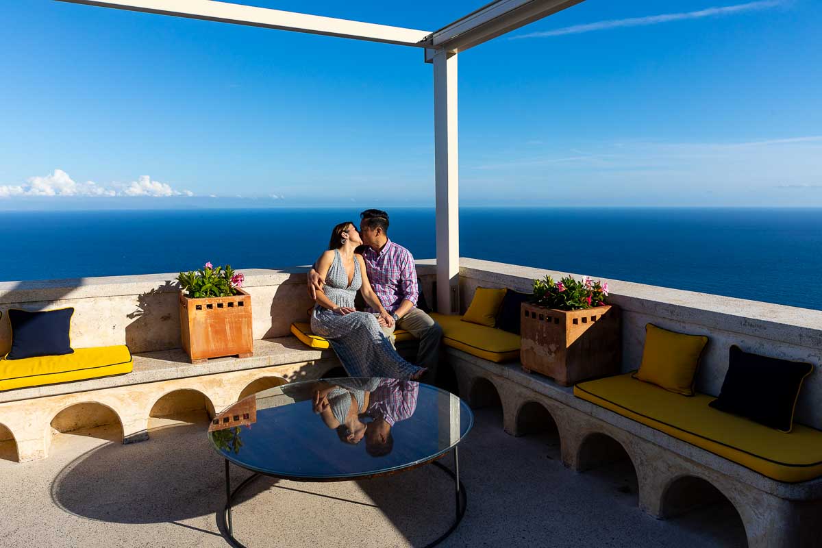 Terrace couple portrait over the water line horizon with their image reflected on the shining table