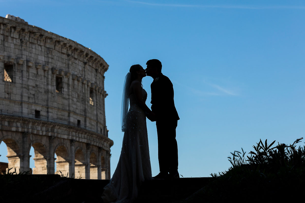 Silhouette image taken with the Roman Colosseum in the background with bright blue sky