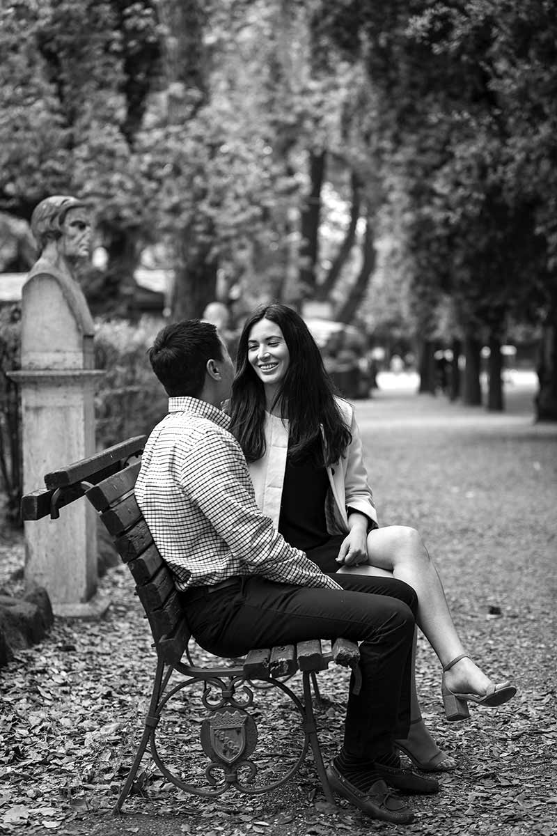 Couple sitting down on a bench during an engagement photo shoot in Villa Borghese park in Rome Italy