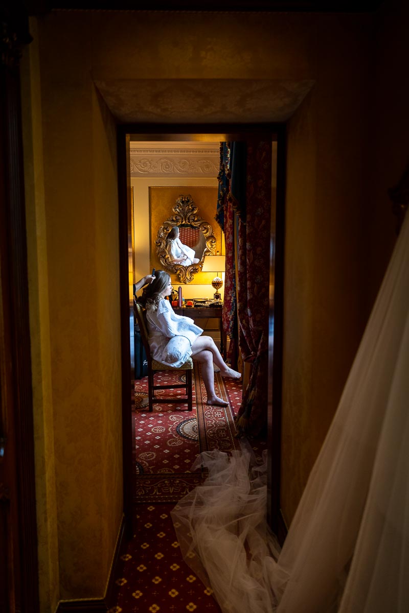 Bridal preparation image. Bride sitting down on a chair by the window. Photography taken from the hall