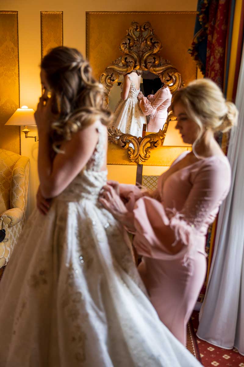 Bridesmaids helping closing the bride's wedding dress