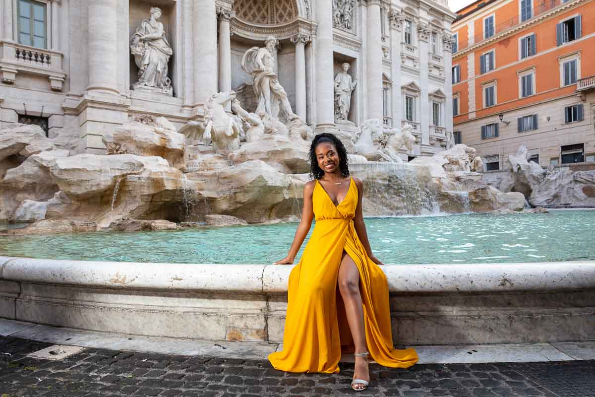 Yellow dress girl posed while sitting on the fountain edge