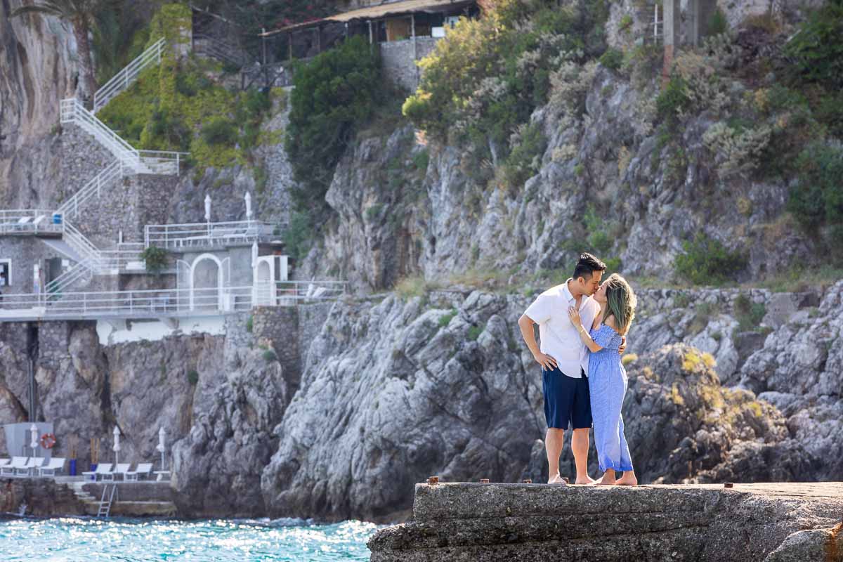 Distance image of a couple kissing while standing on the beach marina of Amalfi