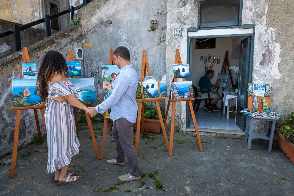 Couple holding hands and looking at paintings made by a local artist