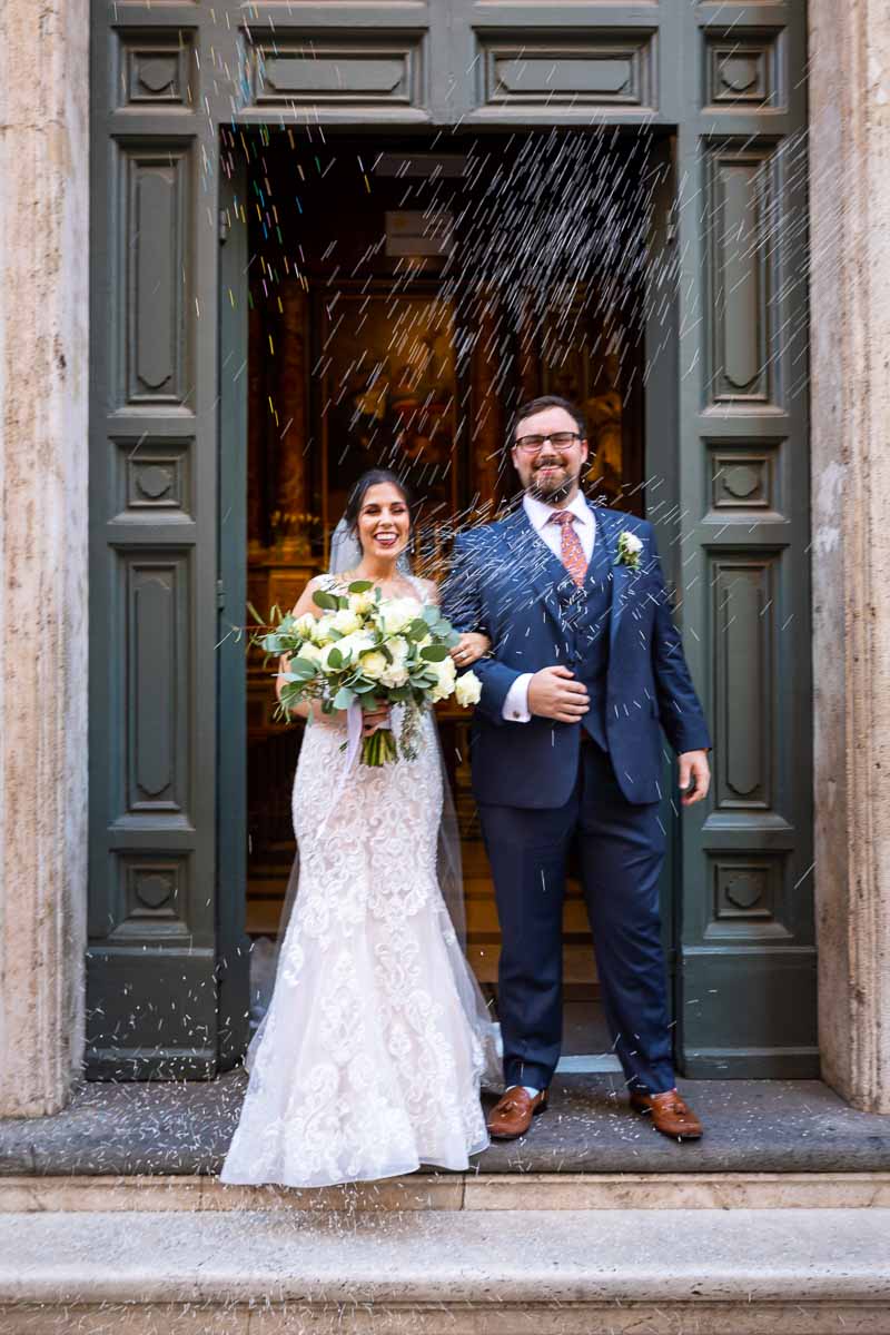 Bride and groom exiting church welcomed by the throwing of the wedding rice