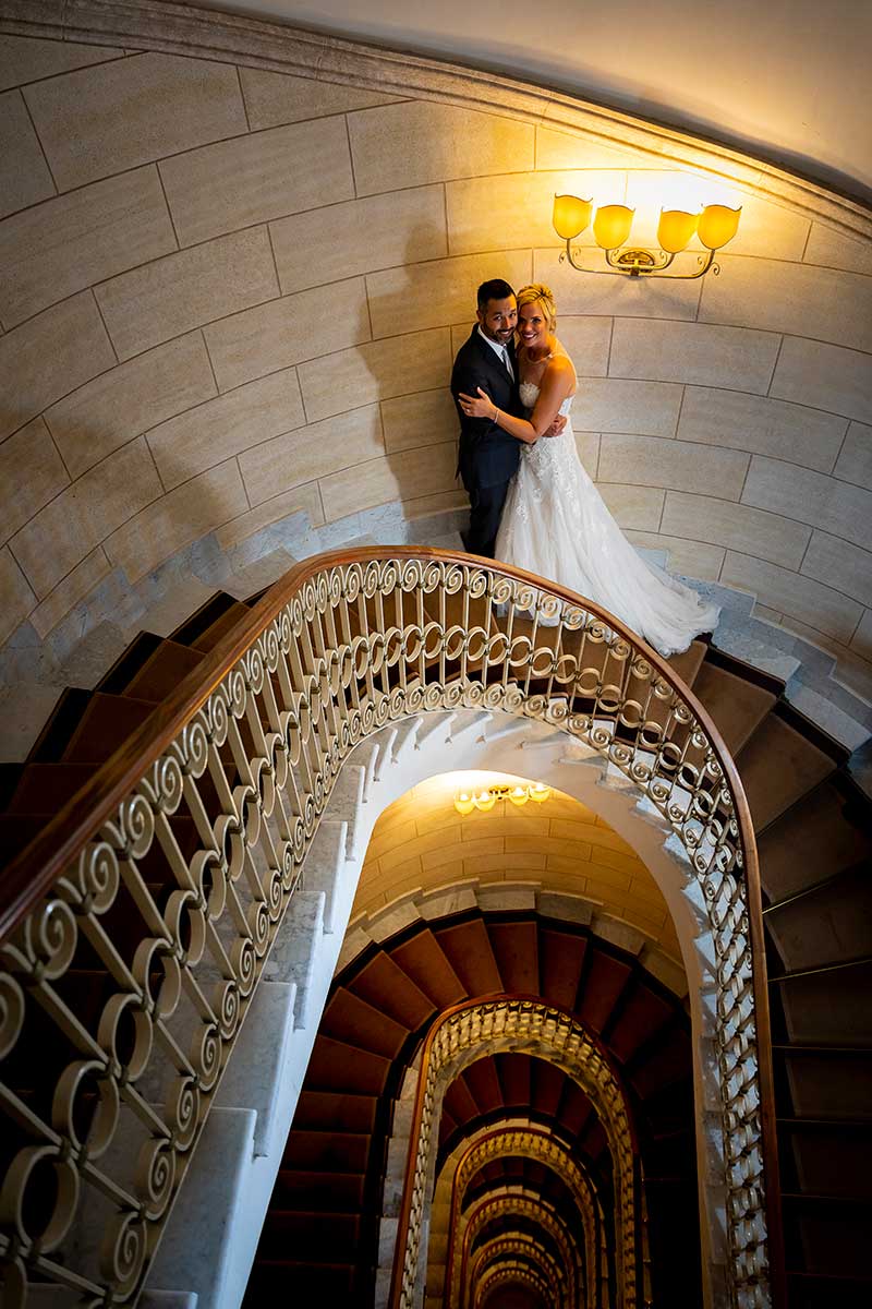 Newlyweds posing underneath light on a spiral staircase