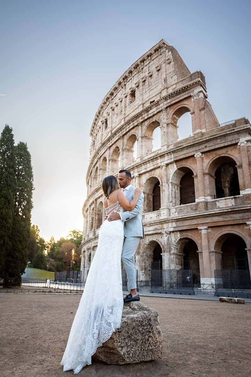 Newlyweds portrait standing on an ancient rock in front of the iconic Colosseum monument