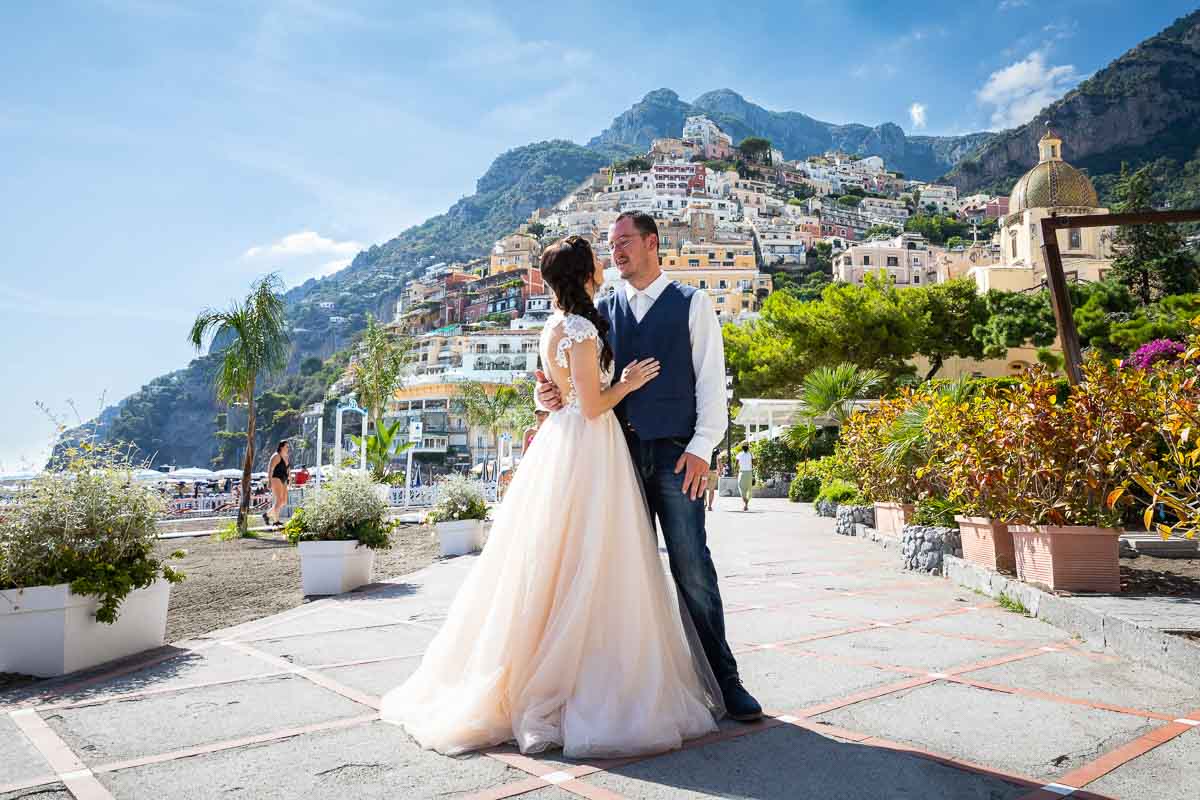 Bride and groom posing together on the boardwalk beach of the town of Positano in the heart of the Amalfi coast. Image by the Andrea Matone photographer studio