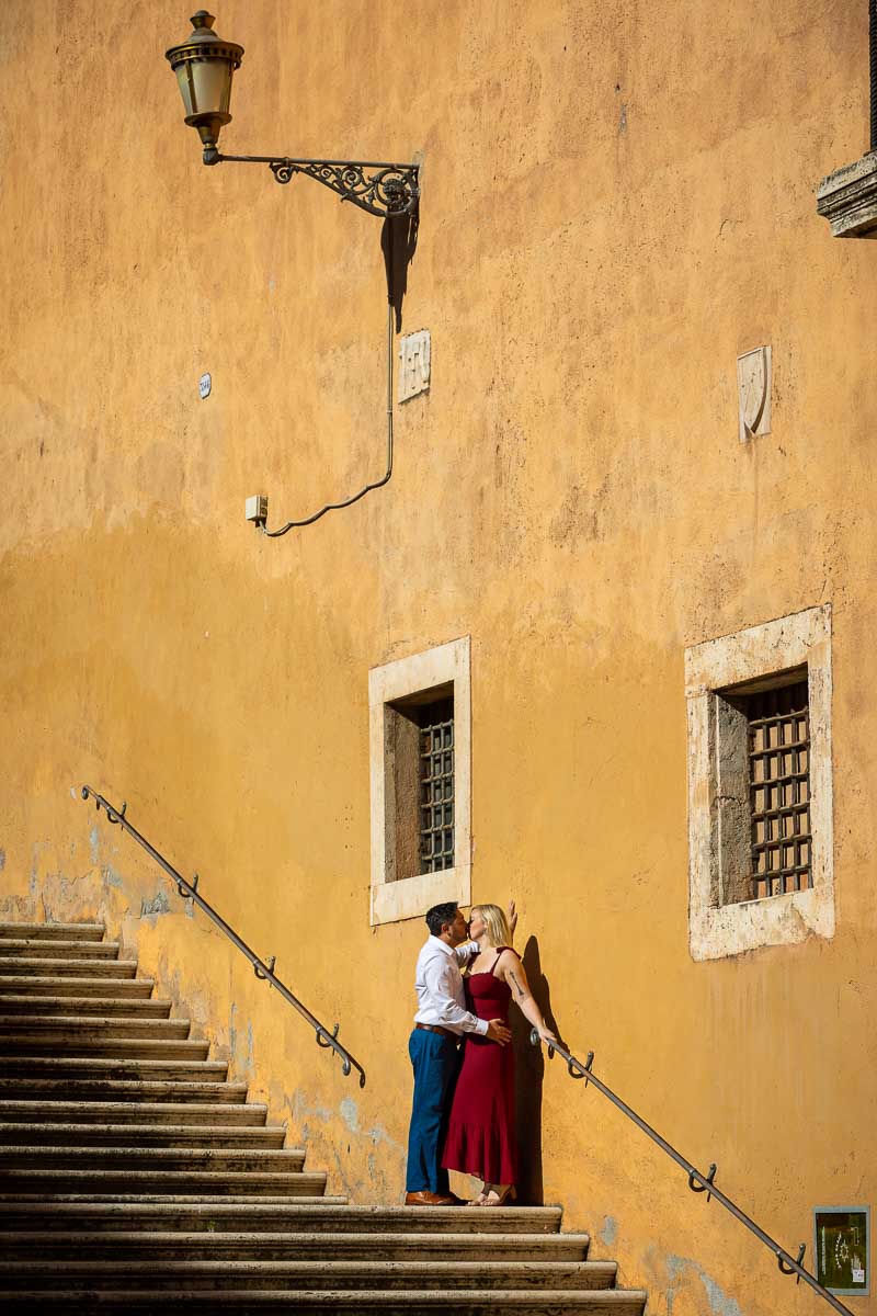 Posed on a wide staircase leaning on the wall framed picture of an engagement with light pole above