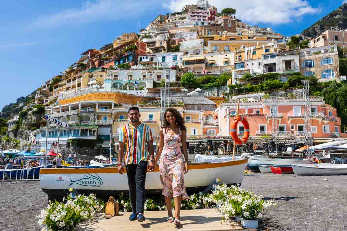 Walking together holding hands with a characteristic boat in the background and the hill town