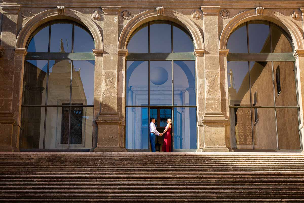 Holding hands together and standing underneath the staircase entrance of Campidoglio in Rome Italy