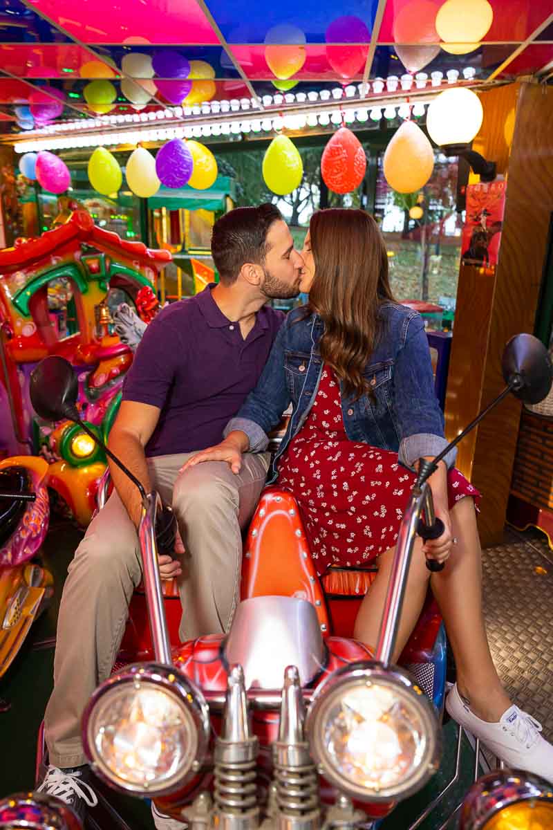 Couple kissing on an amusement ride of a motorcycle for two