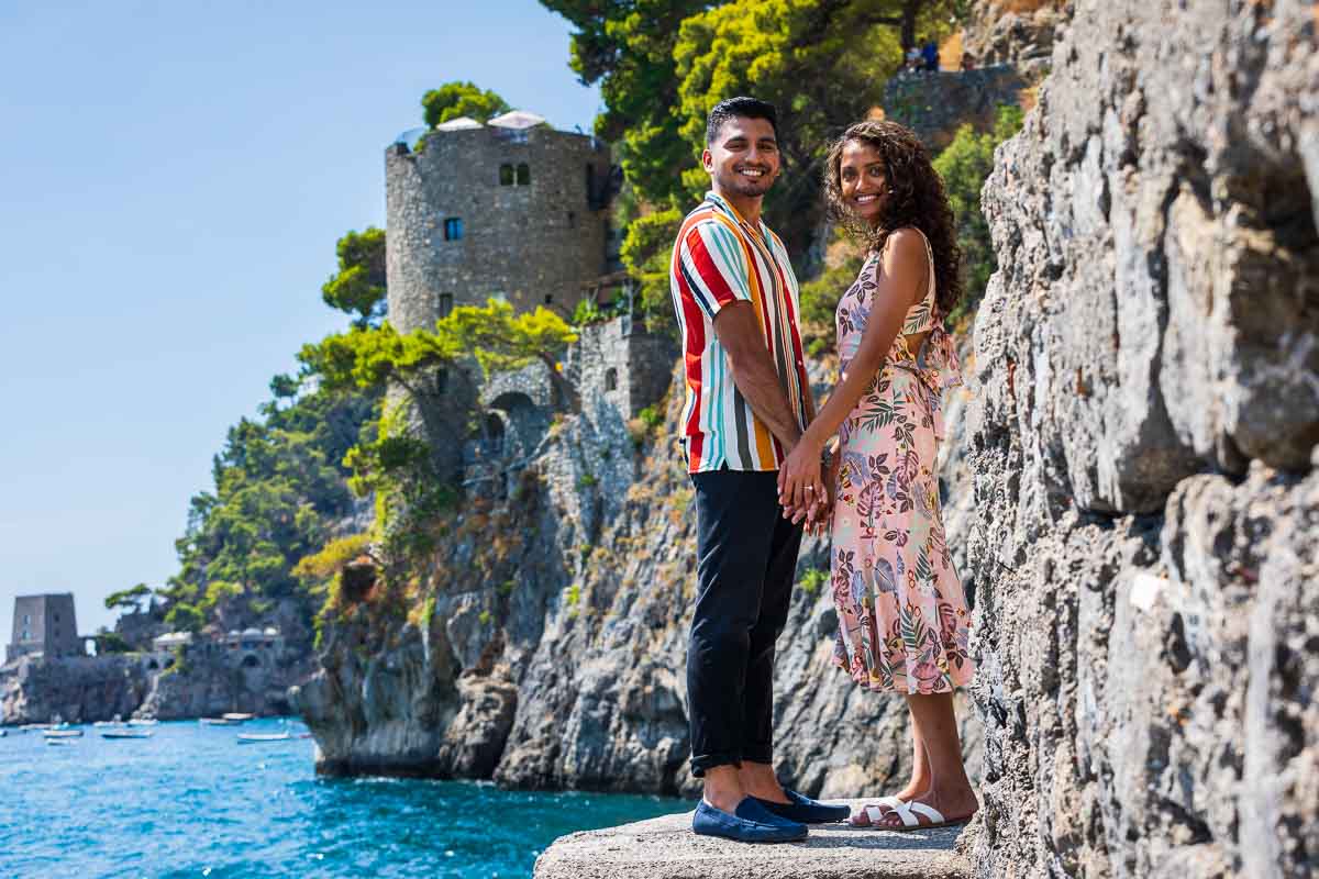 Standing on top of the stairs holding hands and looking back at the camera during an engagement photoshoot in Positano