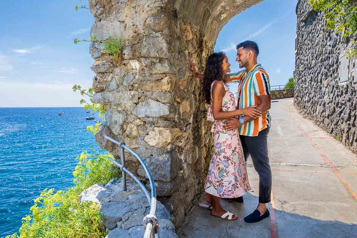 Standing next to each other under an ancient rock arc bridge over the coast passageway