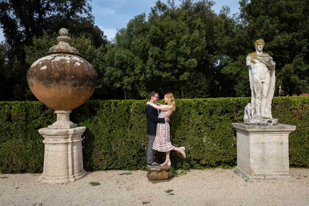 Rome engagement photoshoot posed on a stand in between marble statues and ornaments