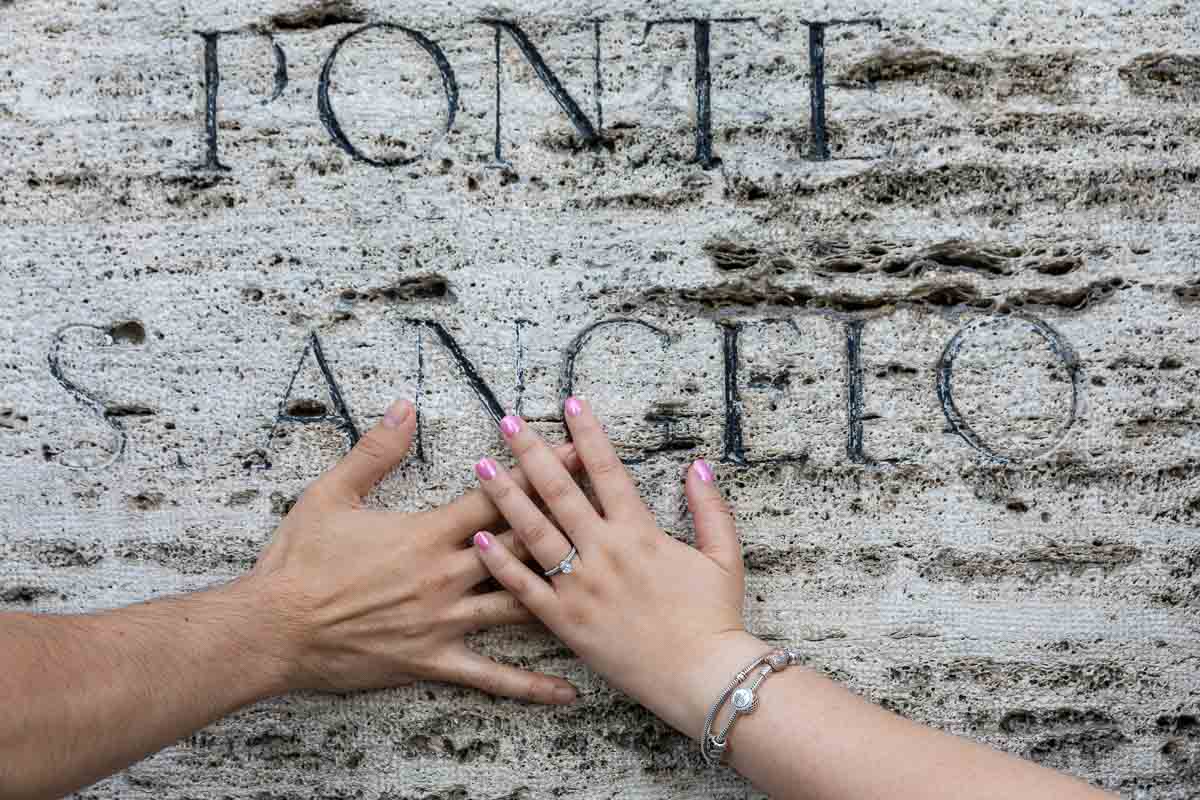 Close up of the engagement ring worn on the hand on top of the ancient marble sign