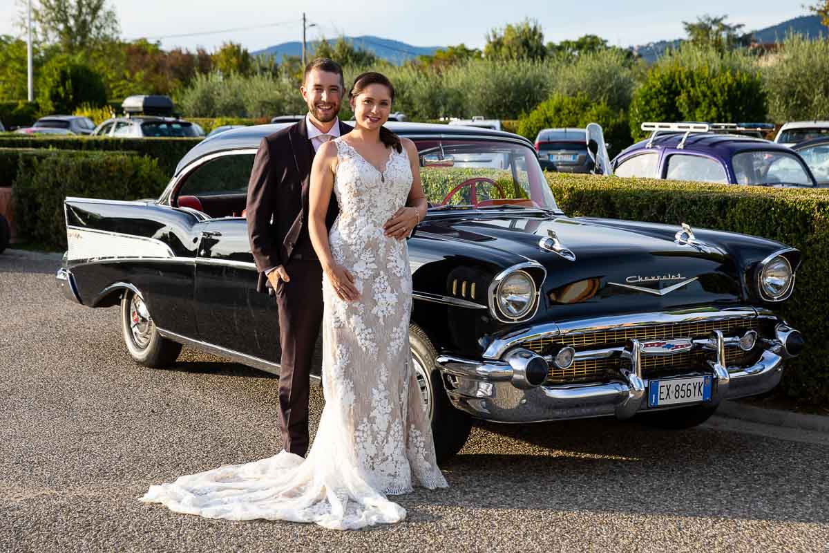 Bride and groom portrait picture taken next to a black Cadillac