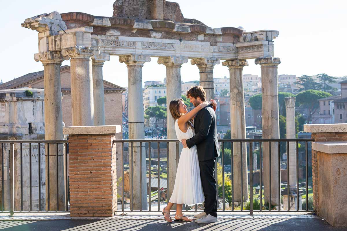 Taking pictures posed together at the Roman Forum with the ancient Rome city in the background 