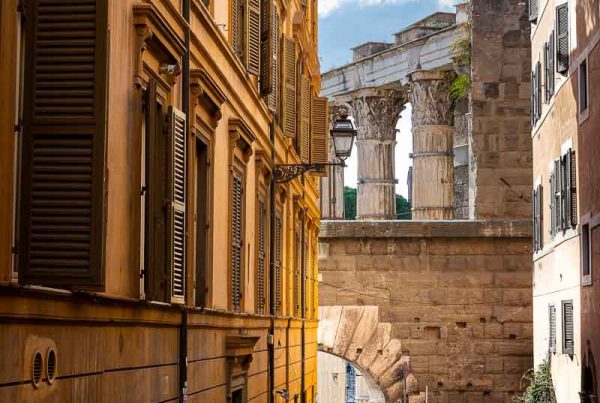 Roman alleyway street with the ancient imperial forum in the far backdrop. Rome, Italy