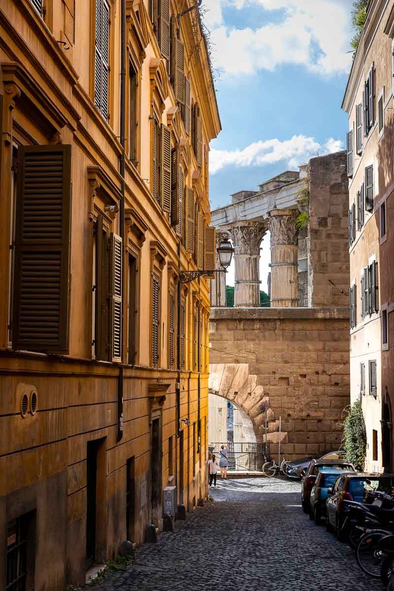 Roman alleyway street with the ancient imperial forum in the far backdrop. Rome, Italy