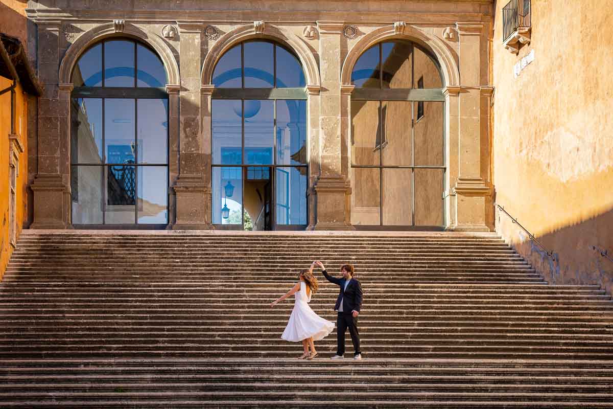 Newlyweds practicing dance moves on a wide staircase during a couple photoshoot