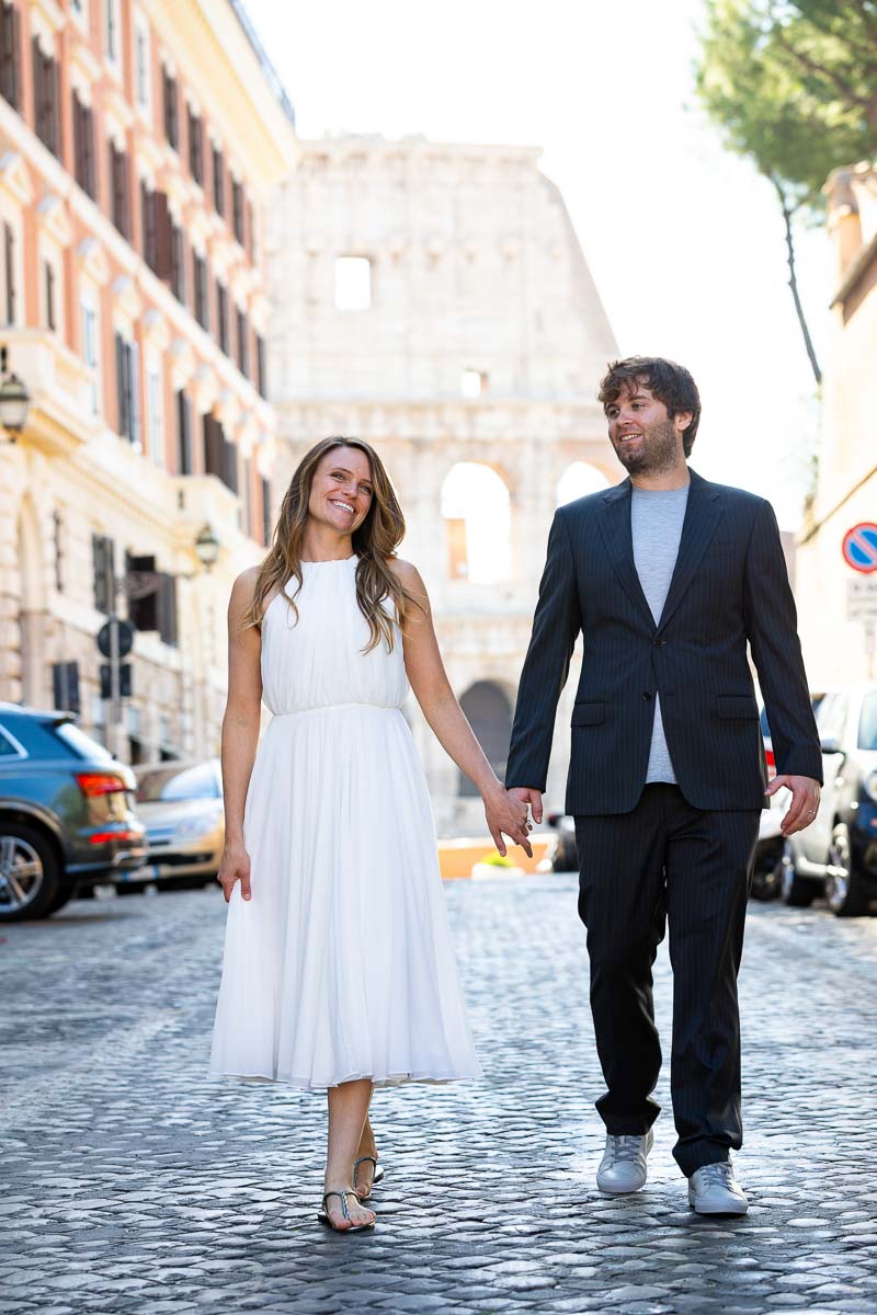 Newlyweds walking together and strolling the roman streets with the unique and iconic monument in the background